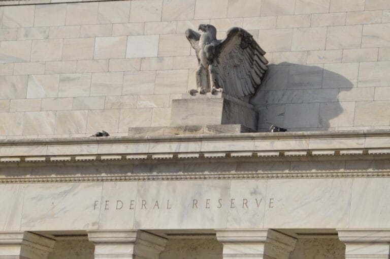 Federal Reserve building with crypto symbols overlay, illustrating Federal Reserve crypto policy discussions.